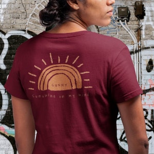 Puede incluir: Una camiseta color granate con un gr&aacute;fico de sol marr&oacute;n y el texto "Sunny Sunshine on my mind".