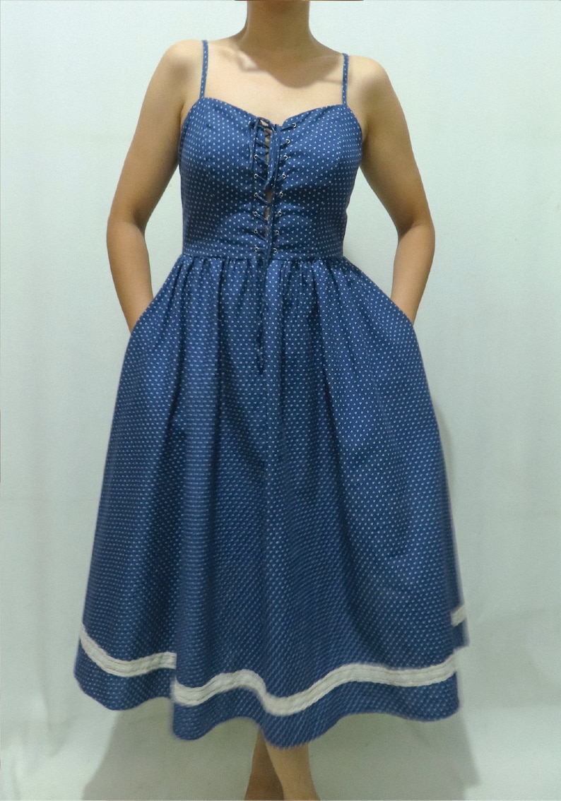 May include: A blue and white polka dot dress with a lace trim and a lace-up bodice.