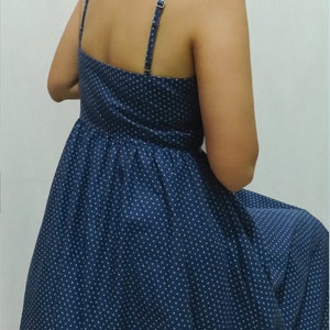 May include: A blue polka dot dress with thin straps. The dress has a fitted bodice and a flowing skirt.