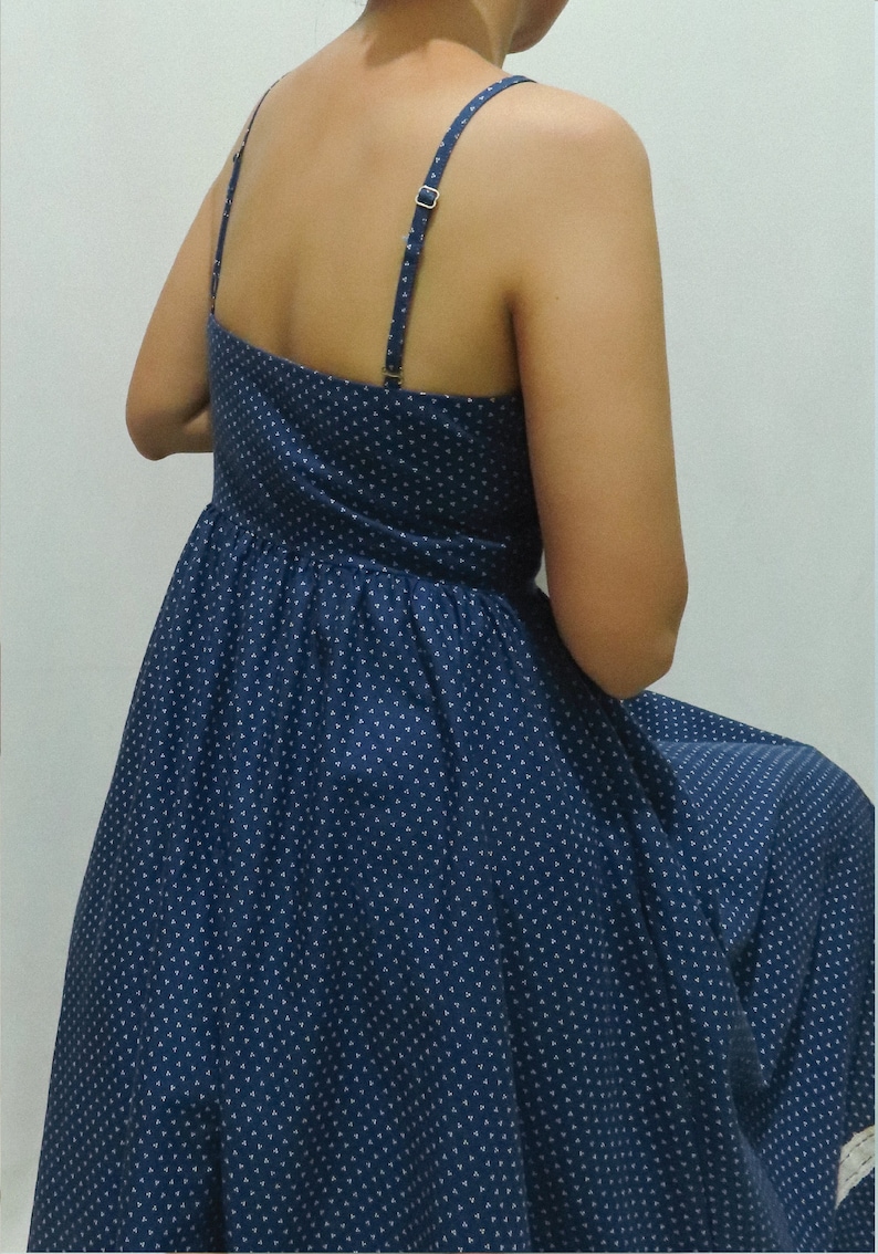 May include: A blue polka dot dress with thin straps. The dress has a fitted bodice and a flowing skirt.