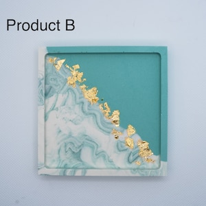 Op de afbeelding: Vierkante teal en witte hars onderzetter met gouden vlokken. De onderzetter heeft een marmerpatroon.