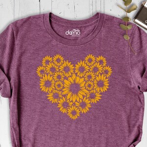 May include: A purple t-shirt with a heart-shaped design made of yellow sunflowers.