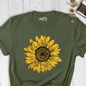以下が含まれることがあります： 黄色のひまわり柄の緑色のTシャツ。クルーネックと半袖です。
