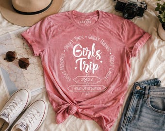 May include: A dusty rose short-sleeve t-shirt featuring white text that reads Girls Trip, Great Times, Great Friends, Great Laughs, Great Memories, 2026, and Your Destination, with a graphic of two directional signposts.