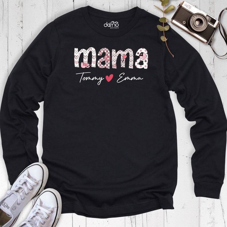 May include: Black long-sleeved shirt with a pink and white patterned "mama" graphic and the text "Tommy &hearts; Emma" below.