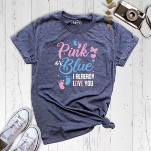 May include: A blue t-shirt with the text "Pink or Blue I Already Love You" in white. The text is surrounded by pink and blue footprints and a butterfly.