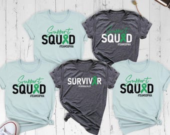 May include: Five short-sleeved t-shirts in light blue and dark gray heather. Four shirts feature the text Support SQUAD with a green ribbon and #TEAMSOPHIA. One dark gray shirt features the text SURVIVOR with a green ribbon and #CEREBRALPALSY.