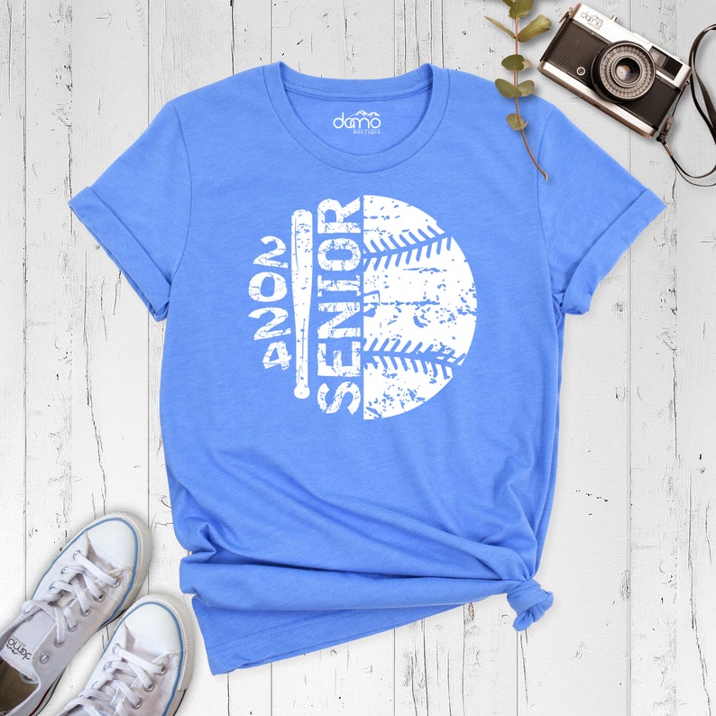 Peut inclure: Un t-shirt bleu clair avec un graphique blanc d'un ballon de baseball et d'une batte avec le texte "Senior 2024".