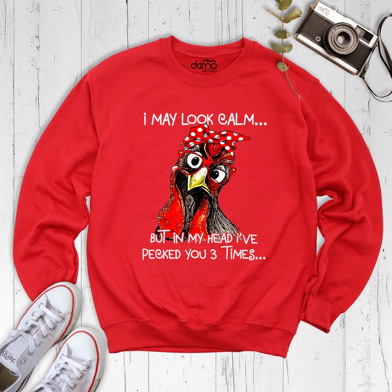 May include: Red sweatshirt with a graphic of a chicken wearing glasses and a red bandana. The text on the sweatshirt reads "I may look calm... But in my head I've pecked you 3 times..."