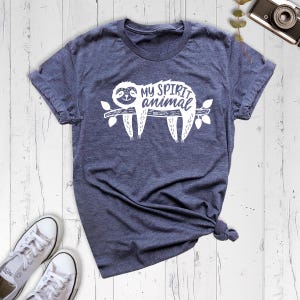 May include: A dark blue t-shirt with a white graphic of a sloth on a branch. The text "My spirit animal" is printed above the sloth.