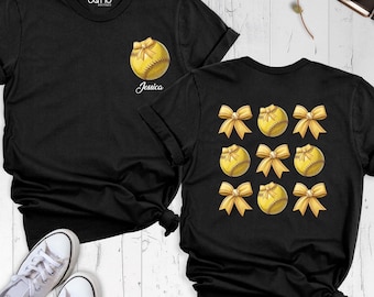 May include: A black t-shirt featuring a small yellow softball with a gold bow on the chest and the name Jessica. The back displays a grid of nine yellow softballs, each adorned with a gold bow, arranged in three rows of three.