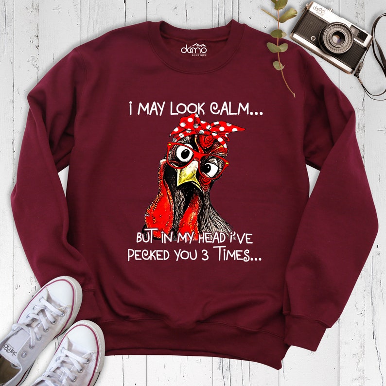 May include: Burgundy sweatshirt with a graphic of a chicken wearing red glasses and a red and white polka dot headband. The text on the sweatshirt reads "I may look calm... But in my head I've pecked you 3 times..."
