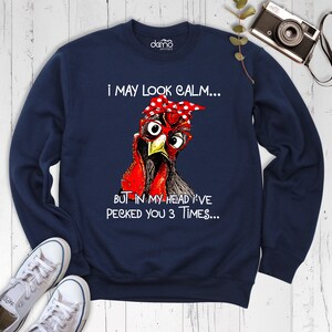May include: Navy blue sweatshirt with a graphic of a chicken wearing glasses and a red polka dot headband. The text on the sweatshirt reads "I may look calm... But in my head I've pecked you 3 times..."