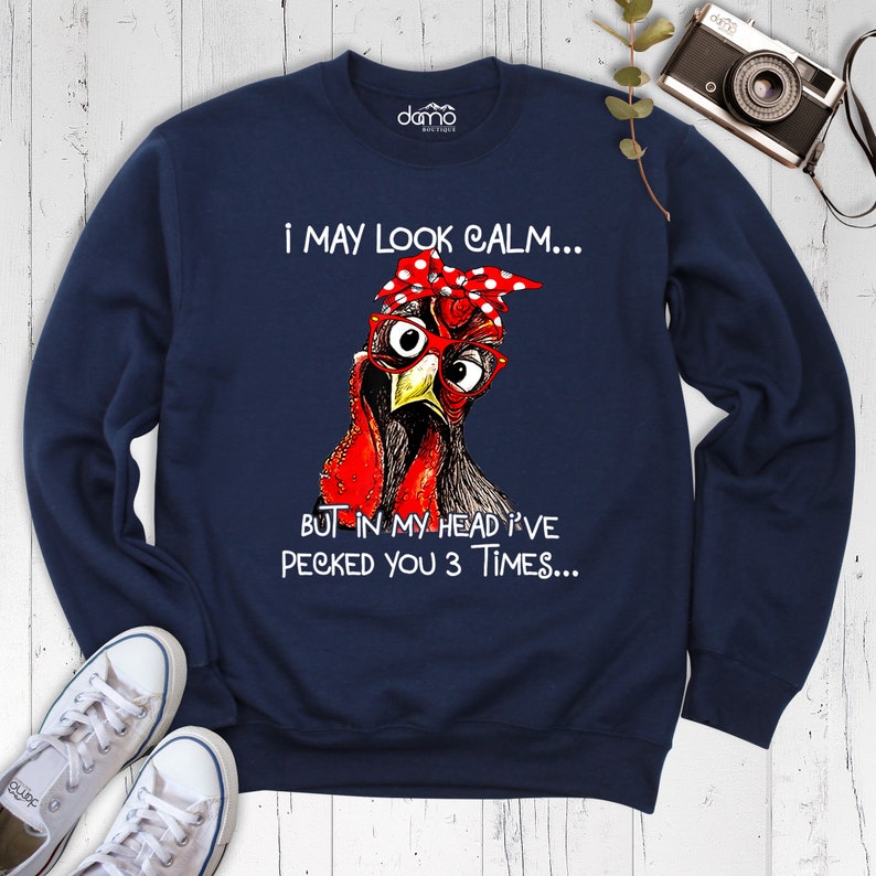May include: Navy blue sweatshirt with a graphic of a chicken wearing glasses and a red polka dot headband. The text on the sweatshirt reads "I may look calm... But in my head I've pecked you 3 times..."