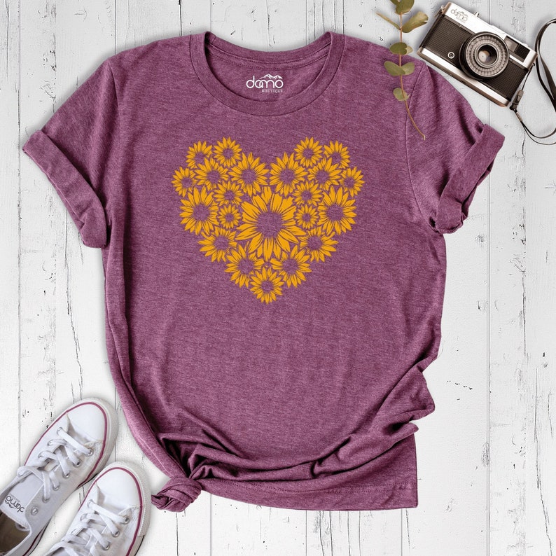 May include: A purple t-shirt with a heart-shaped design made of yellow sunflowers.