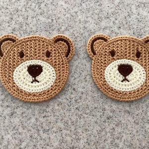 May include: Two circular crochet bear face appliques featuring light brown yarn for the head and ears, with a cream-coloured circular muzzle area. Each bear has dark brown embroidered eyes, a dark brown nose, and a small stitched mouth detail.