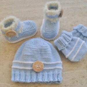 Peut inclure: Un ensemble de bonnet, chaussons et mitaines en tricot bleu pour bébé avec des bordures blanches et des boutons en bois.