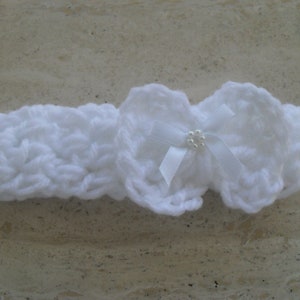 May include: White crocheted headband with a white satin bow and pearl embellishment.