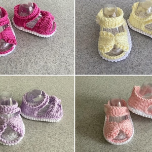 May include: Four pairs of handmade baby sandals in various colors: hot pink, yellow, lavender, and light pink. Each pair features a knitted design with a white sole and strap details. The sandals are displayed on a light gray surface.