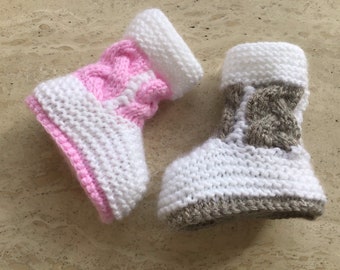 May include: Two pairs of knitted baby booties. One pair is pink and white, the other is gray and white.