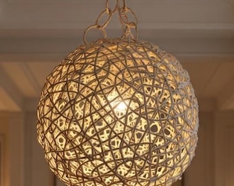 May include: A spherical pendant light fixture constructed from interwoven light-colored rope or twine, suspended by a matching chain. The structure features a complex, knotted pattern that emits a warm, diffused glow from an internal light source.