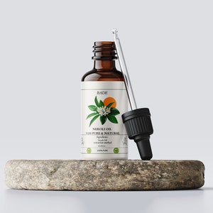May include: A brown glass bottle with a dropper filled with Neroli oil. The bottle has a white label with the text "BADE NEROLI OIL 100% PURE & NATURAL Ingredients: Neroli Oil Extraction method: Distillation 100% PURE" and a drawing of a blooming orange blossom.