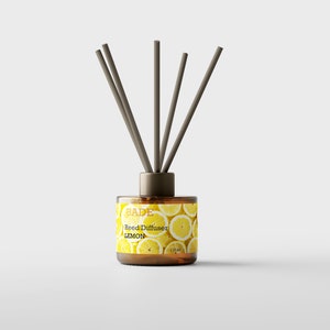 Könnte beinhalten: Eine braune Glasflasche mit einem Zitronen-Motiv-Etikett, auf dem "BADE Reed Diffuser LEMON" steht. Die Flasche hat einen braunen Verschluss mit sechs braunen Schilfrohren, die herausragen.