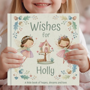 May include: A children's book titled "Wishes for Holly" with illustrations of fairies, a treehouse, and floral decorations. The cover includes the text "A little book of hopes, dreams and love." The book is held by a child.