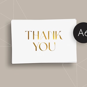 May include: A6 thank you card in white with gold foil lettering. The words "THANK YOU" are displayed in an elegant font. A black circle with the text "A6" is in the upper right corner. The background is a light brown colour with a geometric pattern.