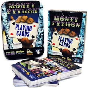 May include: A deck of playing cards featuring images from the Monty Python comedy troupe. The cards are in a blue and black box with the words "Monty Python Playing Cards" on the front. The box is open and the cards are stacked on top of each other.