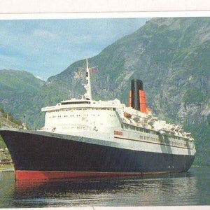 May include: A white and red ocean liner with the word "Caronia" on the side, sailing through a fjord with mountains in the background.