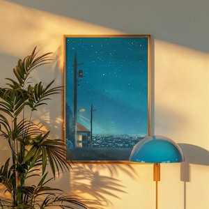 May include: A framed art print depicts a nighttime cityscape under a starry sky. The artwork features a house, telephone poles, and streetlights. The print is displayed on a wall with a blue lamp and a potted plant.