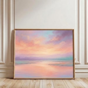 May include: A framed landscape painting depicting a sunset over water. The artwork uses pastel shades of peach, lavender, and turquoise to create a calm scene. The painting is enclosed in a light brown wooden frame.