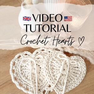May include: Two crocheted hearts in a cream color, with a video tutorial available. The text on the image reads "VIDEO TUTORIAL Crochet Hearts ♥".