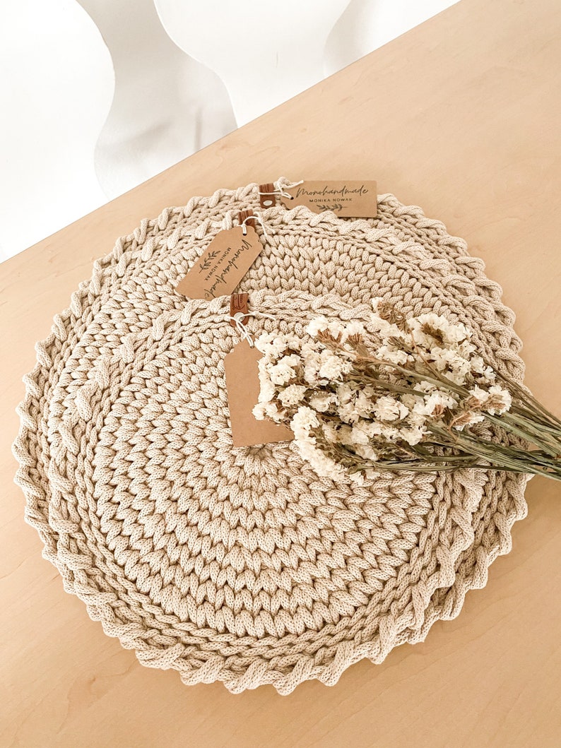 Puede incluir: Dos manteles individuales de crochet beige con una etiqueta marr&oacute;n que dice "Handmade" y una etiqueta que dice "With love from Monika Nowak".