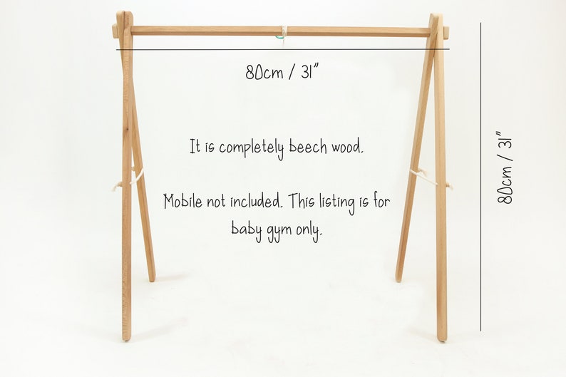 May include: A wooden baby gym stand made of beech wood. The stand is 31 inches wide and 31 inches tall. The text "80cm / 31" is written on the stand. The text "It is completely beech wood. Mobile not included. This listing is for baby gym only." is written below the stand.