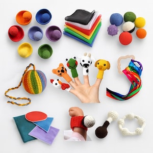 May include: A collection of colorful handmade baby toys, including crocheted finger puppets of animals, a rainbow-striped ball, and various textured balls and bowls. Also includes a wooden ring with colorful ribbons and a crocheted wrist rattle.