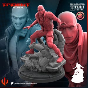 以下が含まれることがあります： タクティカルジャケットとパンツを着用したハゲのキャラクターの赤い3Dプリントミニチュアフィギュア。岩の破片のベースの上にダイナミックなポーズで立っている。背景にはTRIDENT STUDIOおよびPRESUPPORTED PRINT TESTEDというテキストが表示されている。