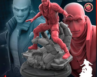May include: A red 3D printed miniature figurine of a bald character in a tactical jacket and pants, posed dynamically on a rocky debris base. The figure features text reading TRIDENT STUDIO and PRESUPPORTED PRINT TESTED on the background.