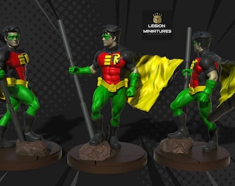 Op de afbeelding: Een geschilderd miniatuurfiguur van Robin, een superheld uit het DC Comics-universum. Robin draagt een rood, geel en groen kostuum met een cape. Hij houdt een staf vast en staat op een rotsachtige basis. Het figuur maakt deel uit van de Legion Miniatures-collectie.