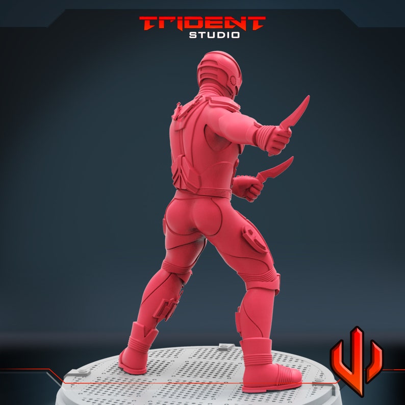 Pu&ograve; includere: Una action figure rossa di un guerriero futuristico con un elmetto e due coltelli. La figura &egrave; in piedi su una base circolare con un motivo a griglia.