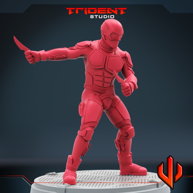 Pu&ograve; includere: Una action figure rossa di un soldato futuristico con un elmetto e due coltelli. La figura &egrave; in piedi su una base grigia con uno sfondo nero.