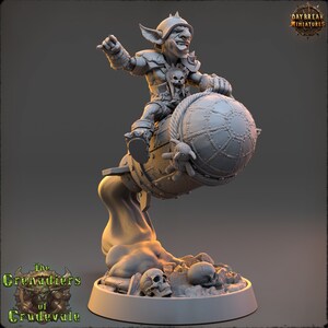 May include: A gray plastic miniature figurine of a goblin riding a bomb. The goblin is wearing armor and holding a weapon. The bomb is decorated with rope and a skull. The figurine is set on a base with skulls and rocks.