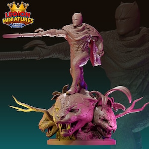 Può includere: Una miniatura stampata in 3D di una figura di supereroe in piedi su una creatura pantera a più teste. La figura indossa una maschera nera e un mantello. La figura tiene uno scettro nella mano destra. La figura è dipinta di marrone. La creatura pantera è dipinta di rosa.