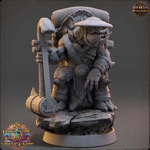 May include: A gray, detailed miniature figurine of a turtle-like creature wearing a straw hat and holding a wooden instrument. The creature is wearing a robe and has a backpack. The miniature is standing on a gray rock base.