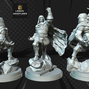 May include: A gray plastic miniature figurine of Doctor Doom, a Marvel Comics supervillain, standing on a rocky base. The figurine is posed with one arm raised in the air, and the other arm is bent at the elbow. The figurine is wearing a long, flowing cape and a mask.