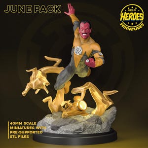 Op de afbeelding: Gedetailleerde miniatuurfiguur van een superheld in een dynamische pose, gekleed in een geel en grijs kostuum. De figuur maakt deel uit van de "June Pack" en is op schaal 40 mm. De basis is grijs en de figuur is omgeven door gouden energie-effecten.