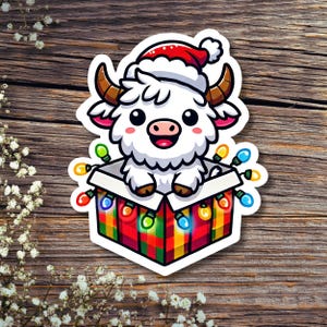 Cute White Highland Christmas Cow in Gift Box Lights, Die-Cut Sticker, Hydro Flask sticker, Tumbler Sticker, Lap top Decal, Kindle Sticker