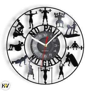 May include: Black vinyl clock with a white face and red hands. The clock is decorated with silhouettes of people exercising and the text "NO PAIN NO GAIN".