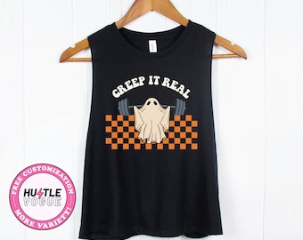 May include: Black sleeveless tank top with a white ghost lifting a barbell with the text "Creep It Real" in orange and white letters. The ghost is on a checkered background with orange and white squares.